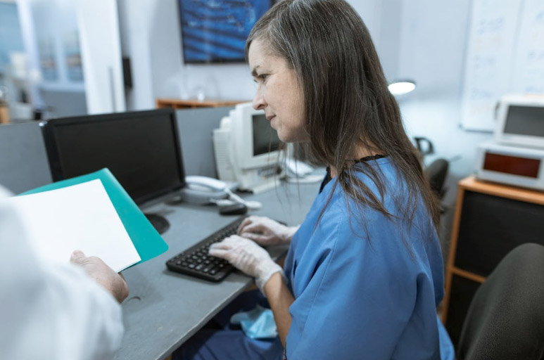 a nurse typing on a keyboard while sitting