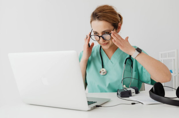 Woman in Teal Scrub Suit Using a Laptop Computer