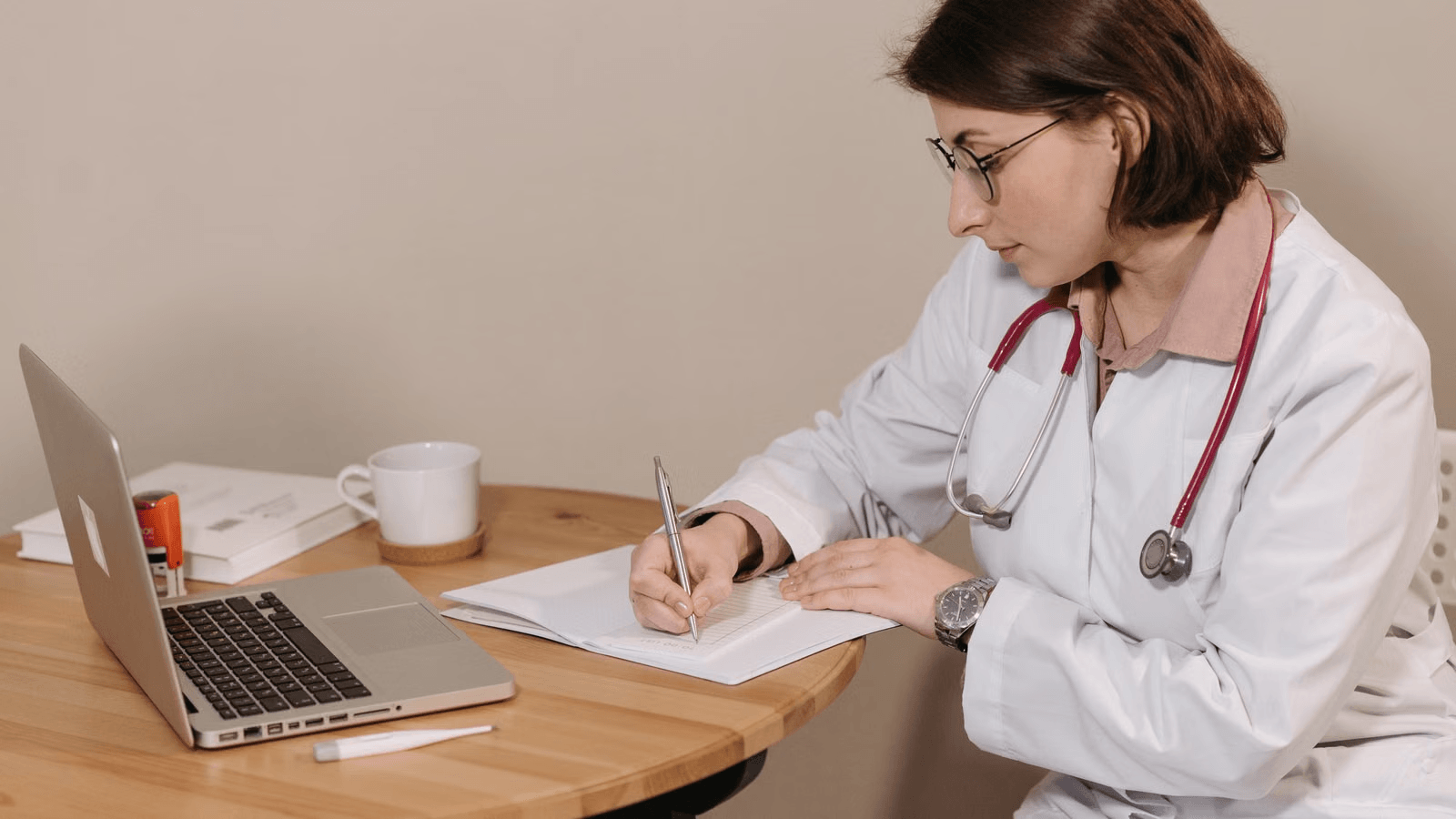 Healthcare provider reviewing notes beside a laptop for ACO quality reporting